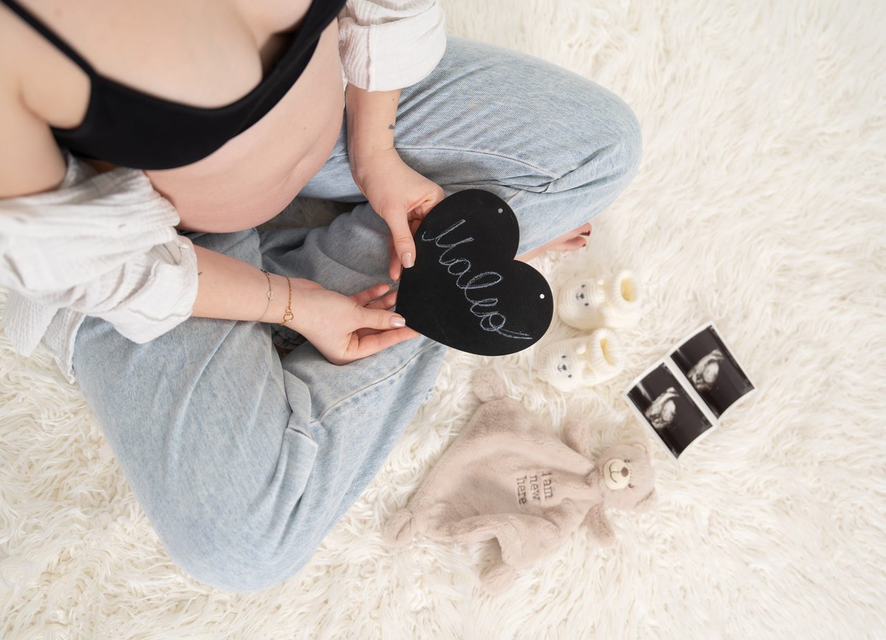 Babybauch-Shooting: Babybauch mit Herz-Schild, Paarhaende, quer 2560px – Photography Ruel, Ebreichsdorf