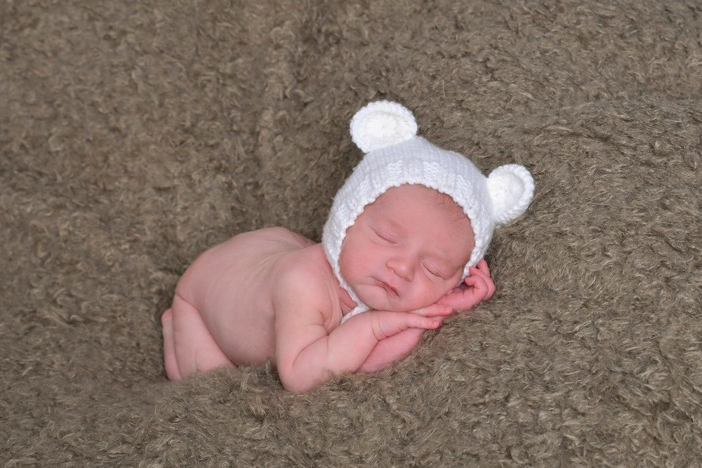 Neugeborenen-Shooting: Newborn mit Baerenmuetze auf Fell (Master) – Photography Ruel, Ebreichsdorf