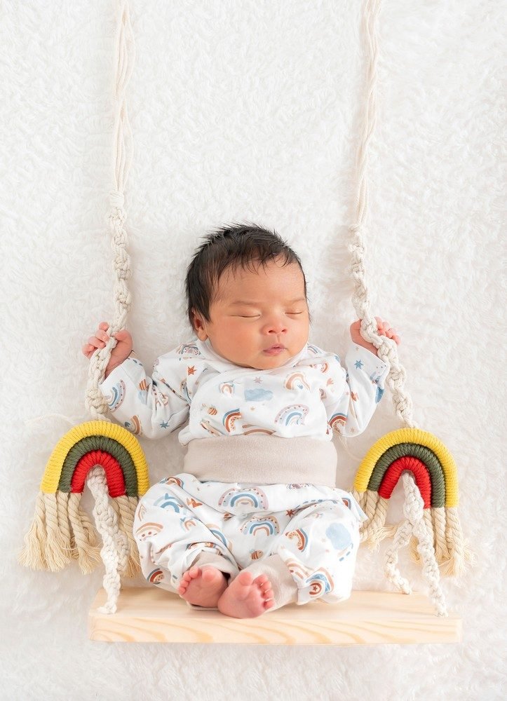 Neugeborenen-Shooting: Newborn Regenbogen-Outfit auf Schaukel (Master) – Photography Ruel, Ebreichsdorf